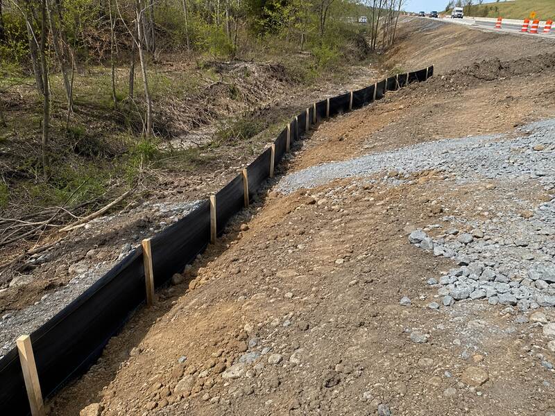 Black silt fence along a roadside slope
