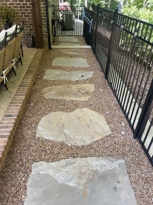 Natural flagstone path in Gravel-Lok stabilized pea gravel curving beside a travertine pool deck