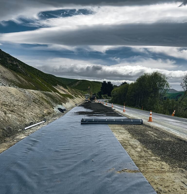Rolling out Mirafi H2Ri geotextile across a road subgrade
