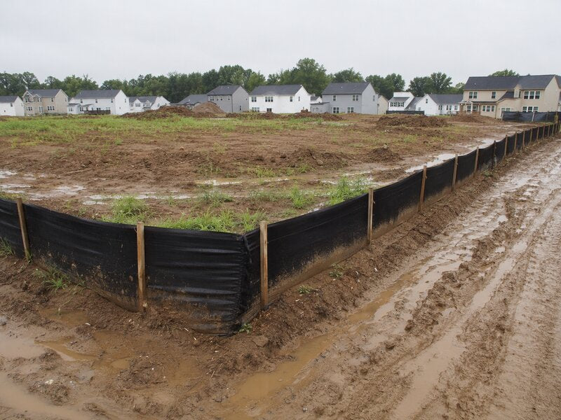 Silt fence at a muddy residential construction site with homes
