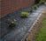 Weed barrier landscape fabric in a planting bed along a brick wall
