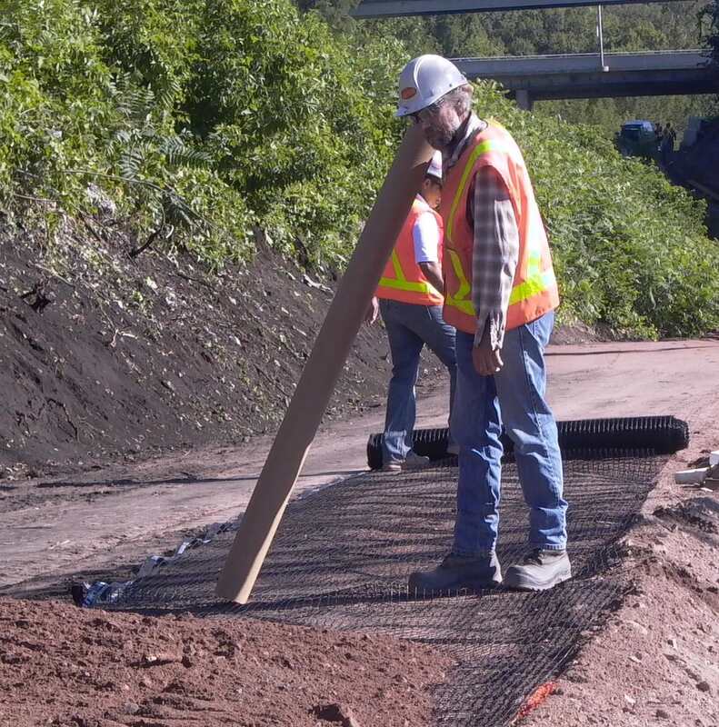 Workers unrolling Solmax Miragrid XT geogrid
